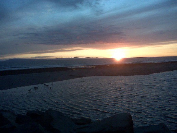 A sunset over the ocean with a dark sky